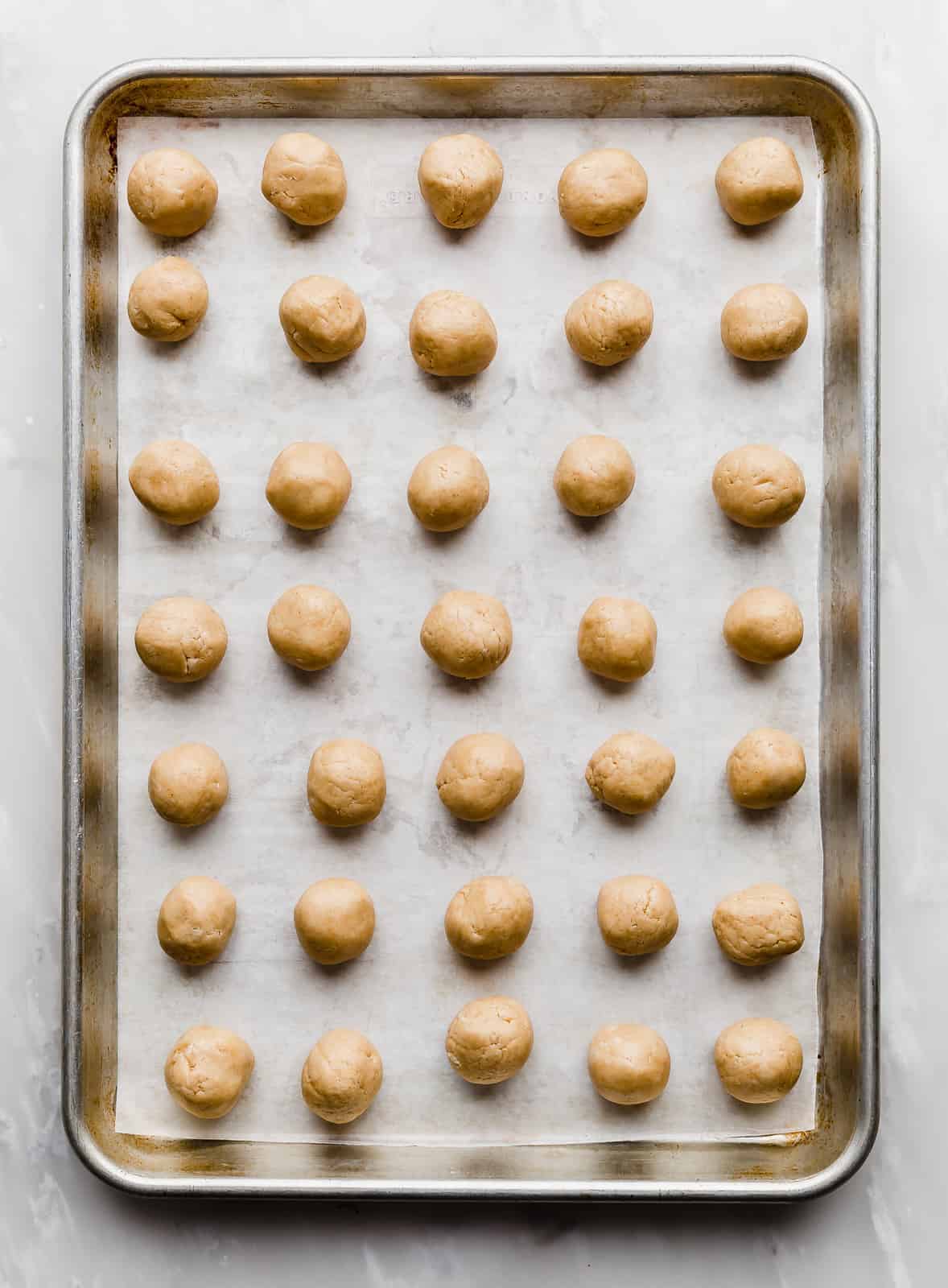 Small, round, peanut butter buckeyes lined up on a baking sheet.