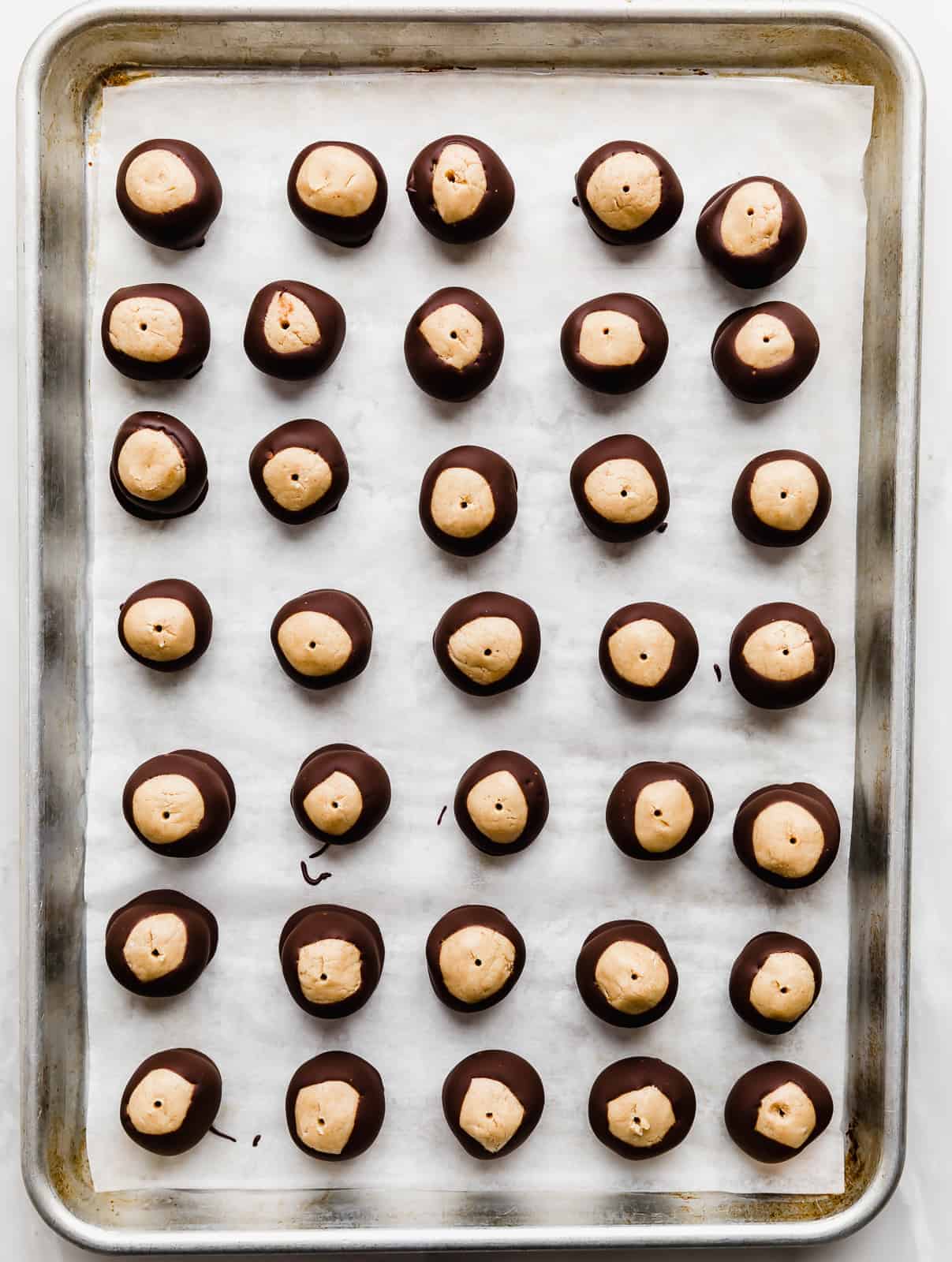 Chocolate dipped buckeyes on a baking sheet.