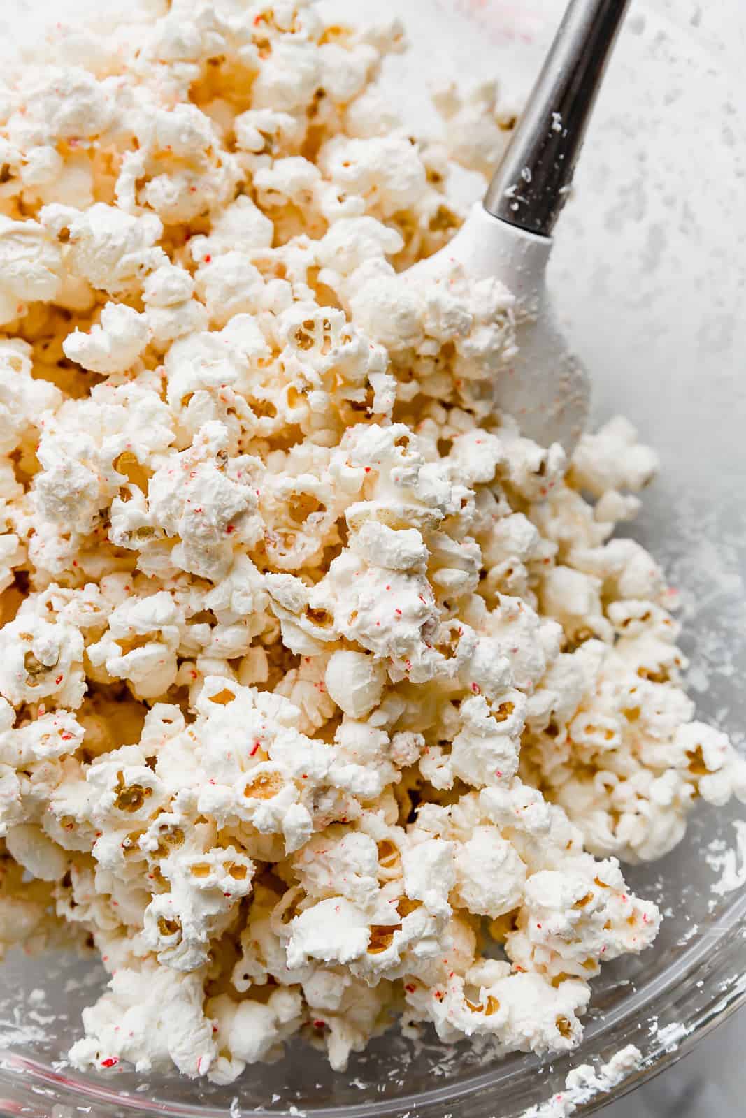 A close up photo of popped popcorn covered in white chocolate and crushed candy canes.