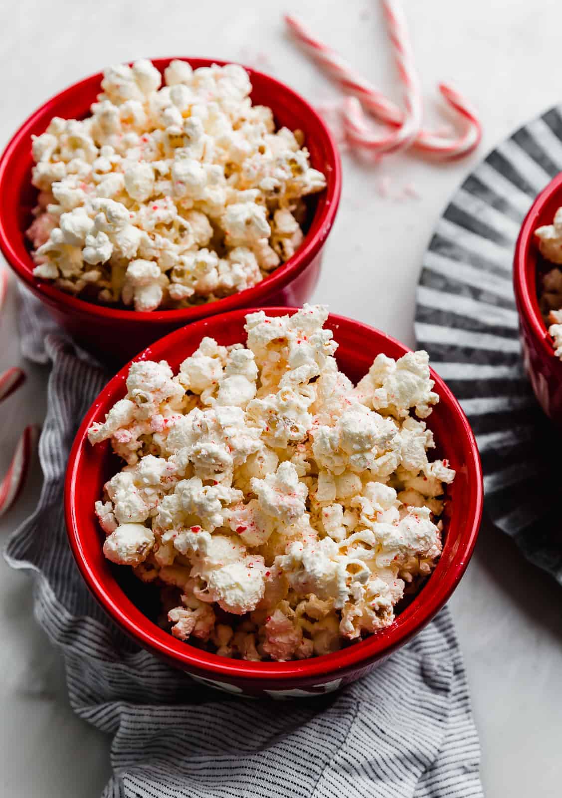 Two red bowls full of popped popcorn.