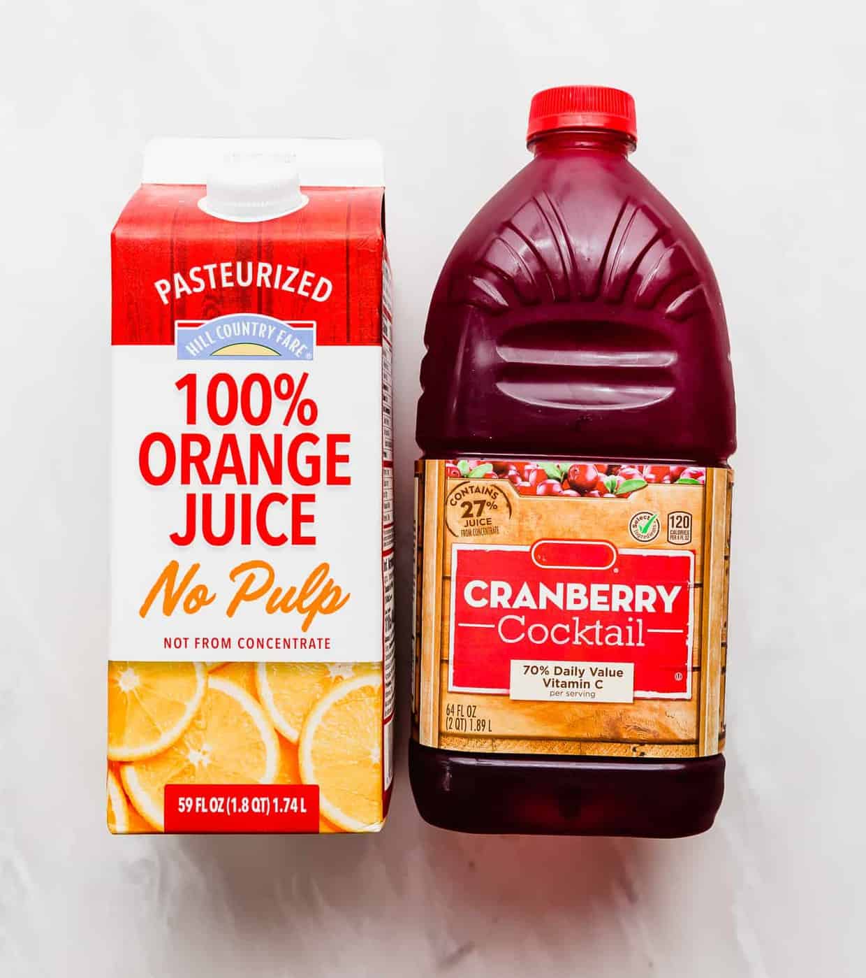 A carton of orange juice and cranberry juice cocktail against a white background.