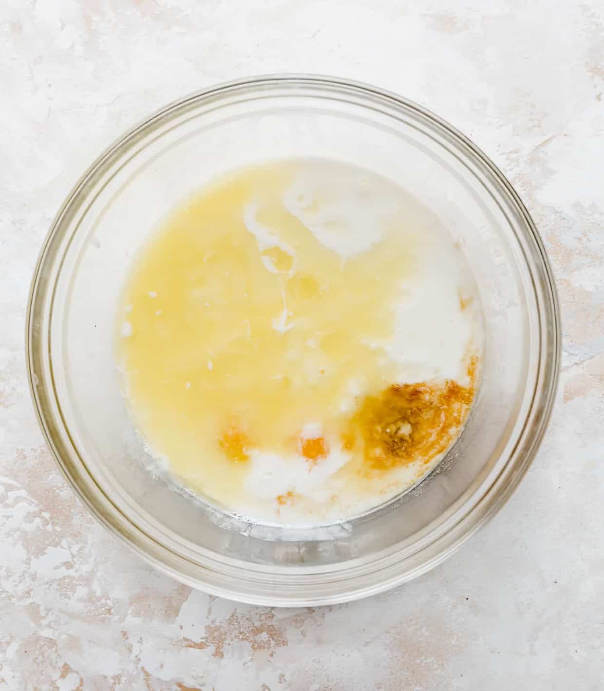 A glass bowl full of buttermilk, melted butter, vanilla, and 2 egg yolks.