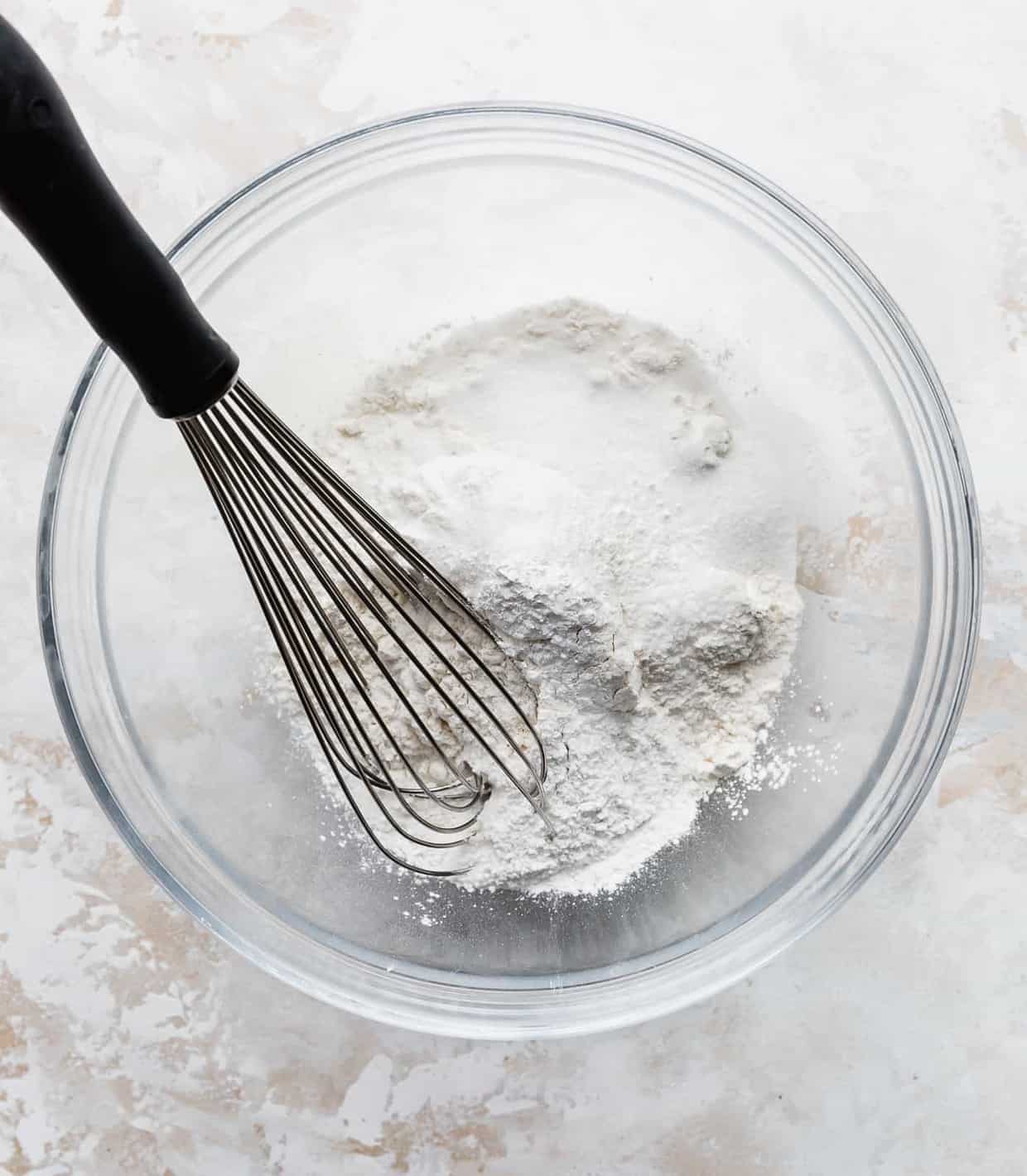 White dry ingredients in a glass bowl against a white background.