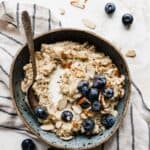 A bowl of Steel Cut Oats on a white background with blueberries and nuts.