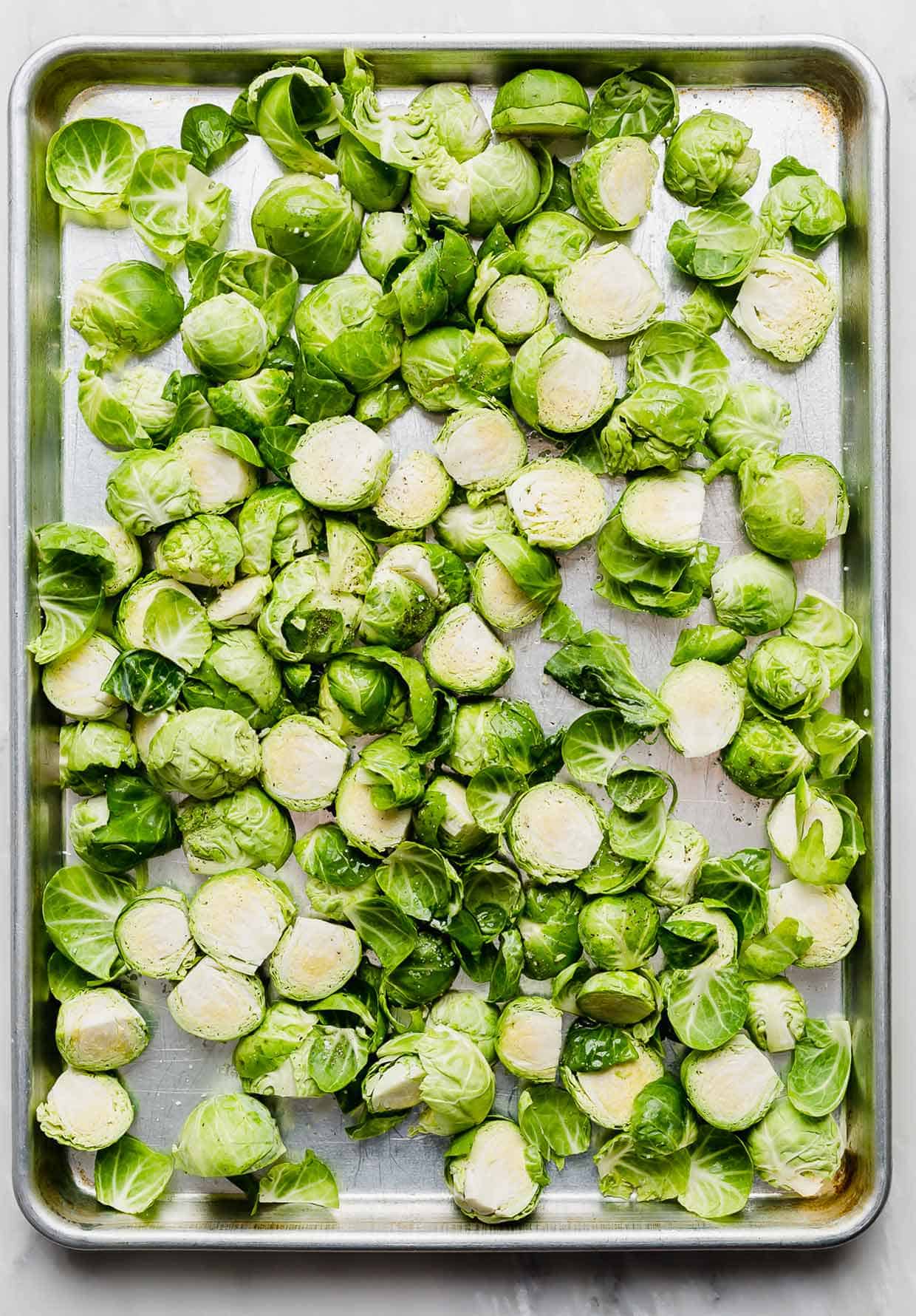 A sheet pan with chopped Brussels sprouts on it.