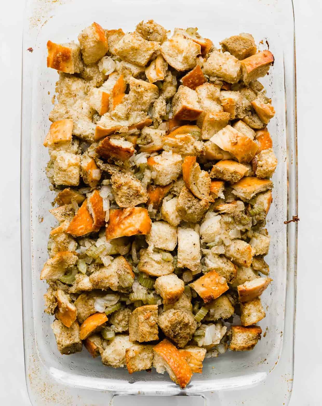 Golden brown thanksgiving stuffing in a 13x9 inch clear baking dish.