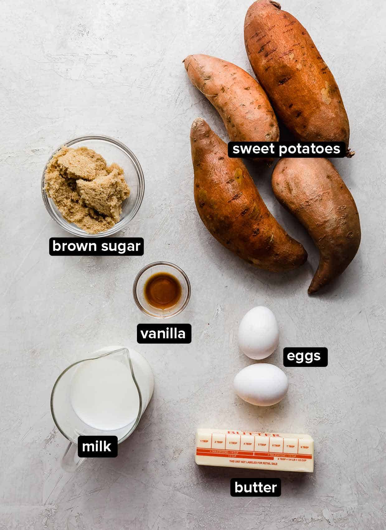 Easy Sweet Potato Casserole ingredients on a light gray background: orange yams, milk, butter, eggs, vanilla, and brown sugar.