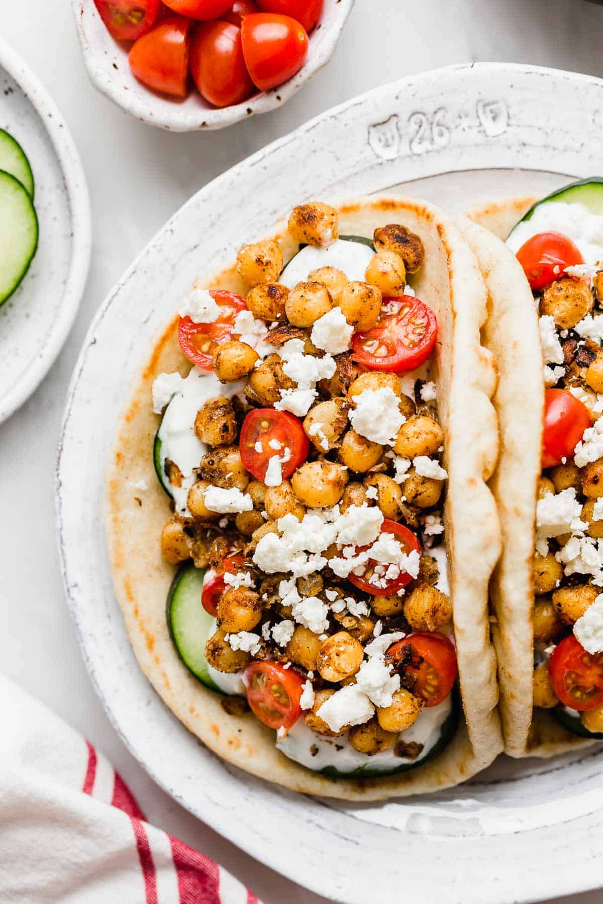 Overhead photo of crispy Chickpea Gyros on flatbread on a white plate.