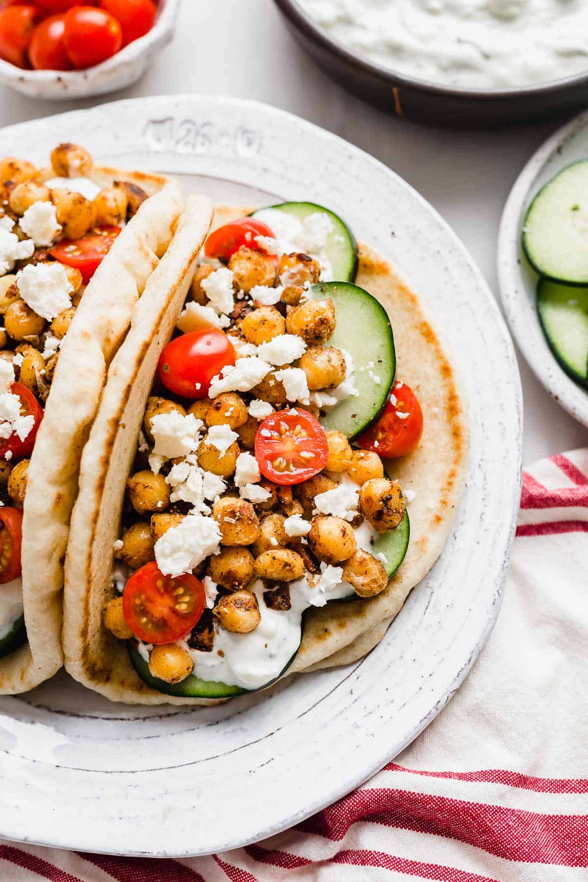 Chickpea Gyros on a white plate topped with cucumbers, cherry tomatoes, and feta cheese.