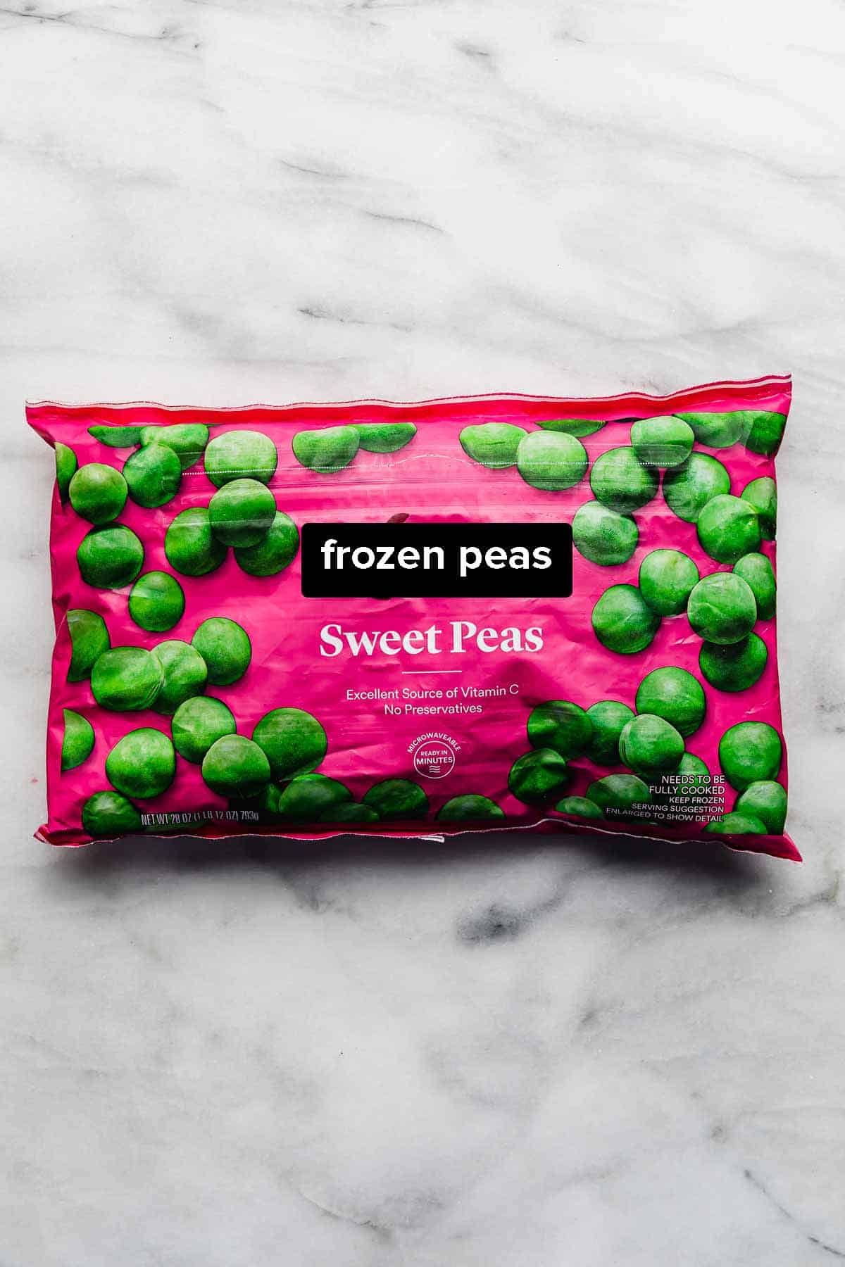 A bag of frozen peas on a white marble background used to show How to Cook Frozen Peas.