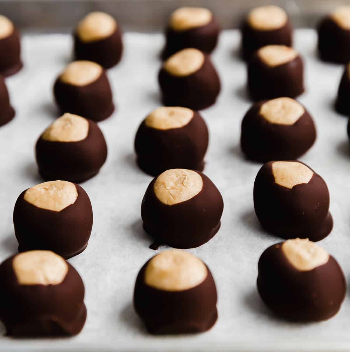 Chocolate dipped Buckeye balls on a white parchment paper.