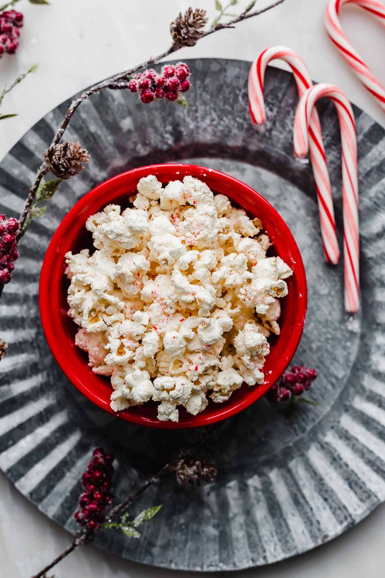 Candy Cane Popcorn in a red bowl on a gray metal large plate.