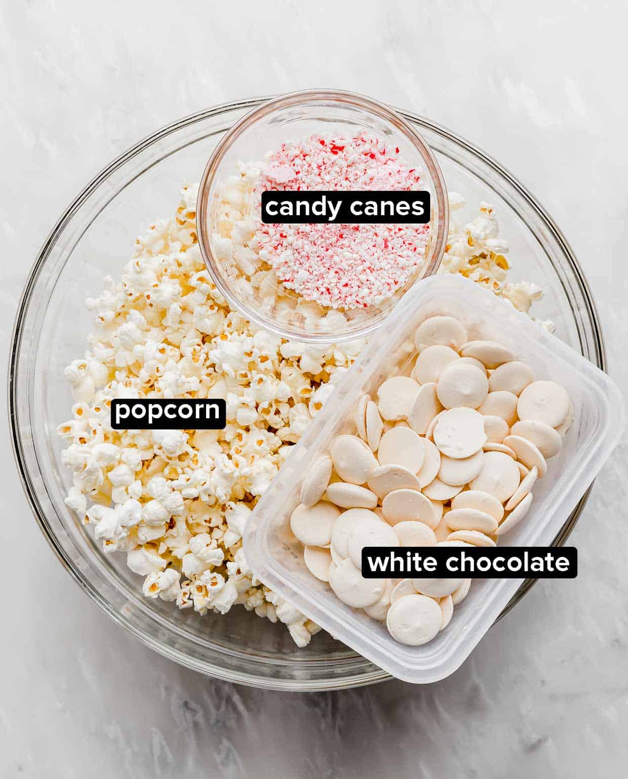 Candy Cane Popcorn ingredients on a white background: popcorn, crushed candy canes, and white chocolate.