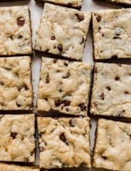 Chewy Chocolate Chip Cookie Bars lined up on a white background.