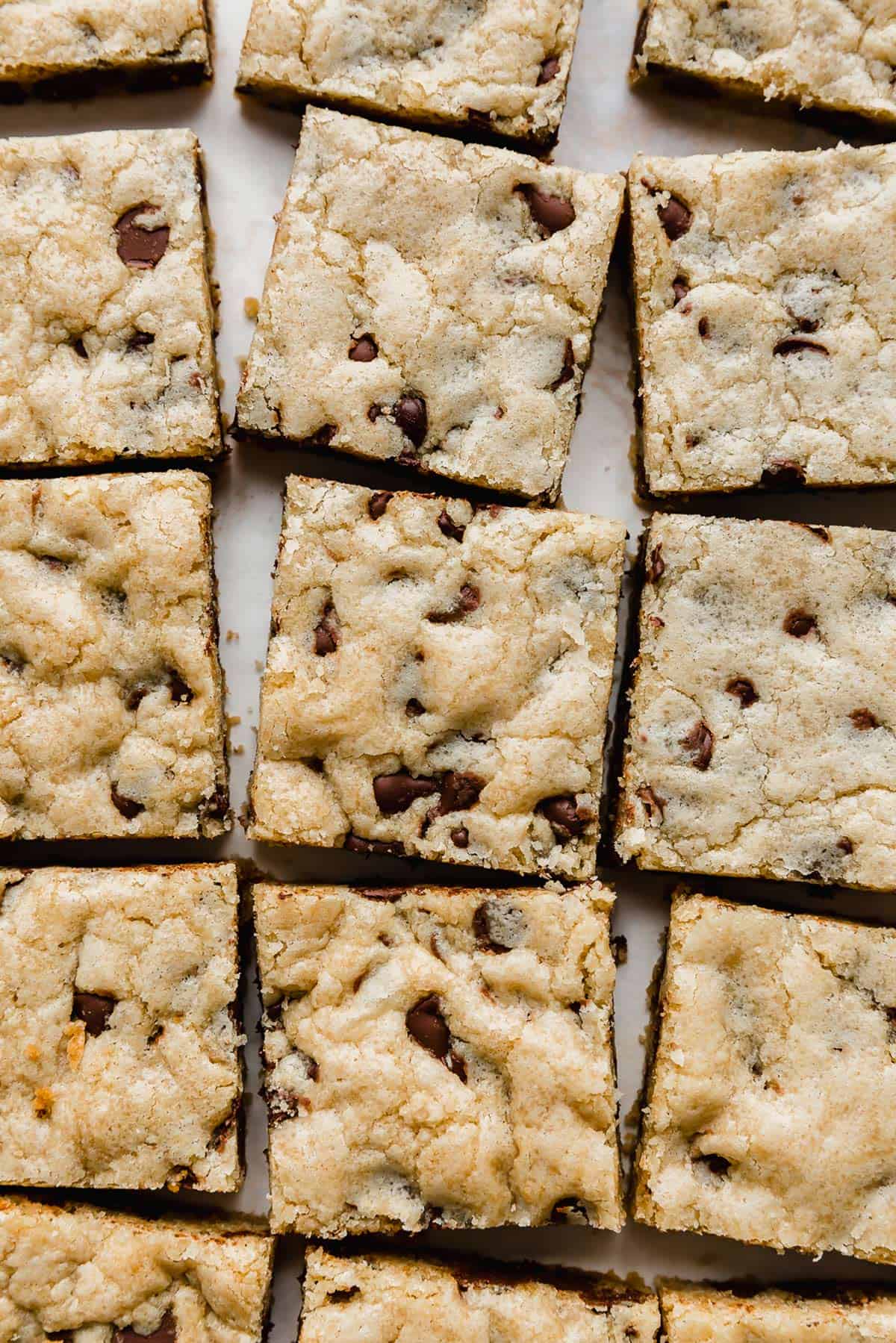 Chewy Chocolate Chip Cookie Bars lined up on a white background.