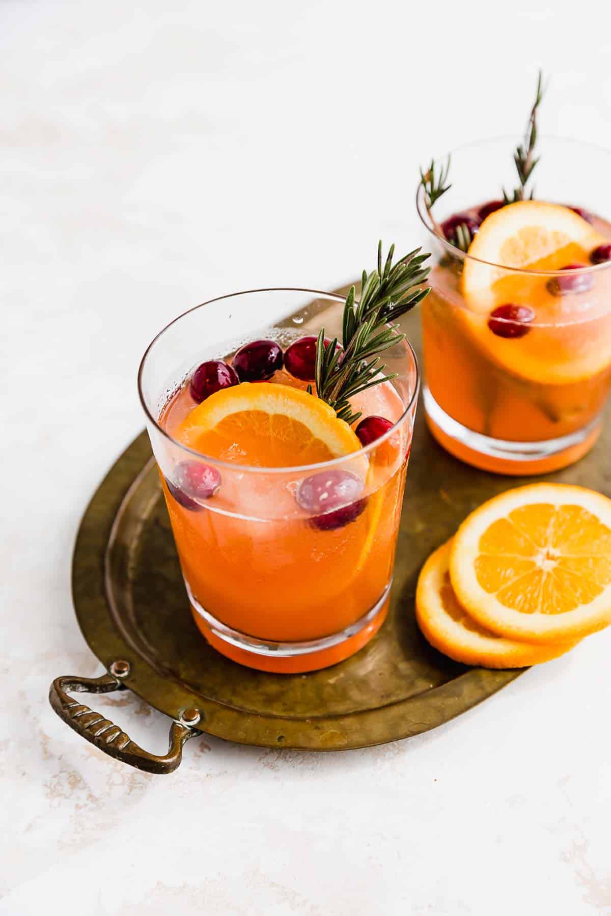 A glass filled with Christmas Punch on a bronze oval tray.