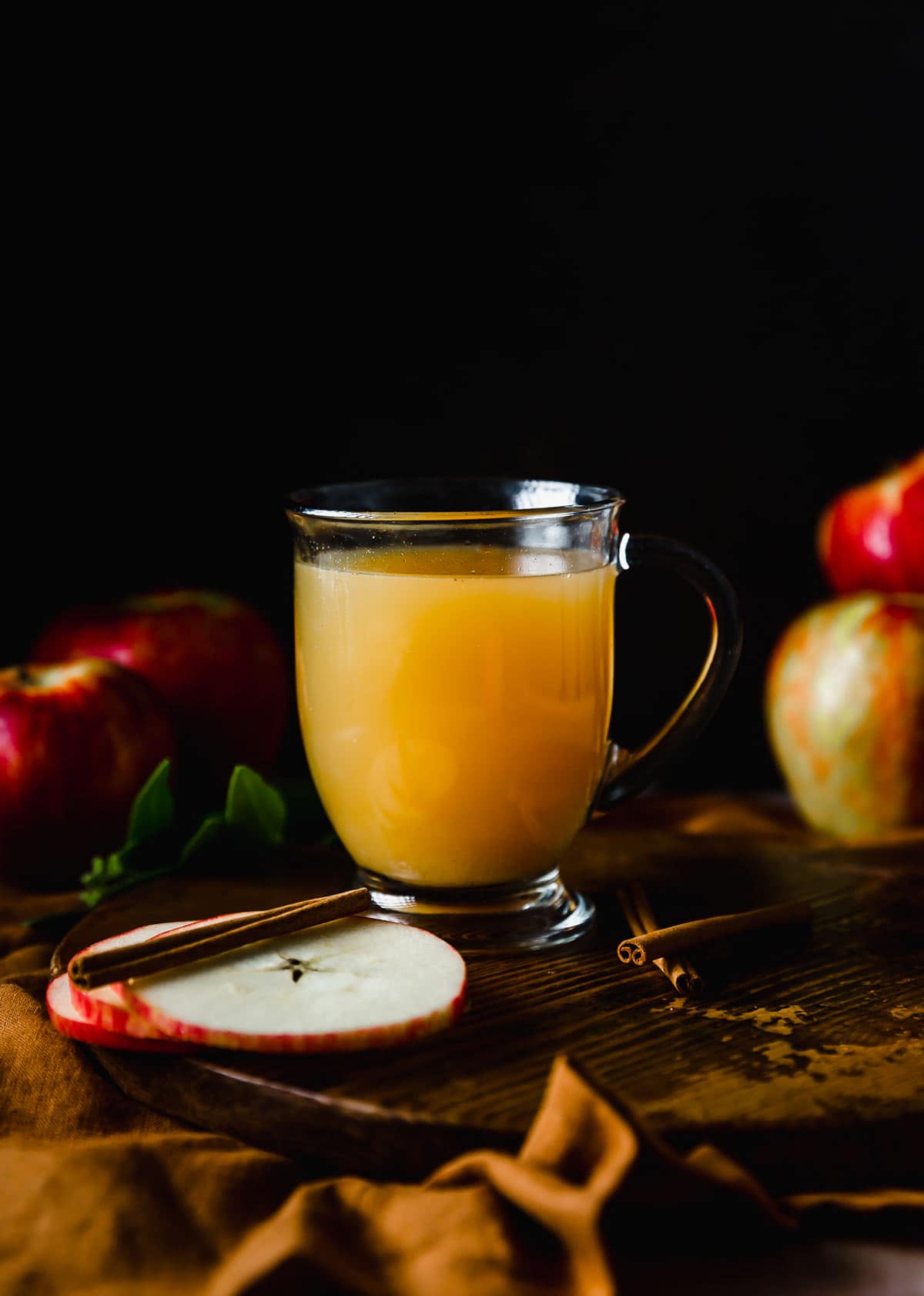 Hot Wassail in a clear mug against a black background.