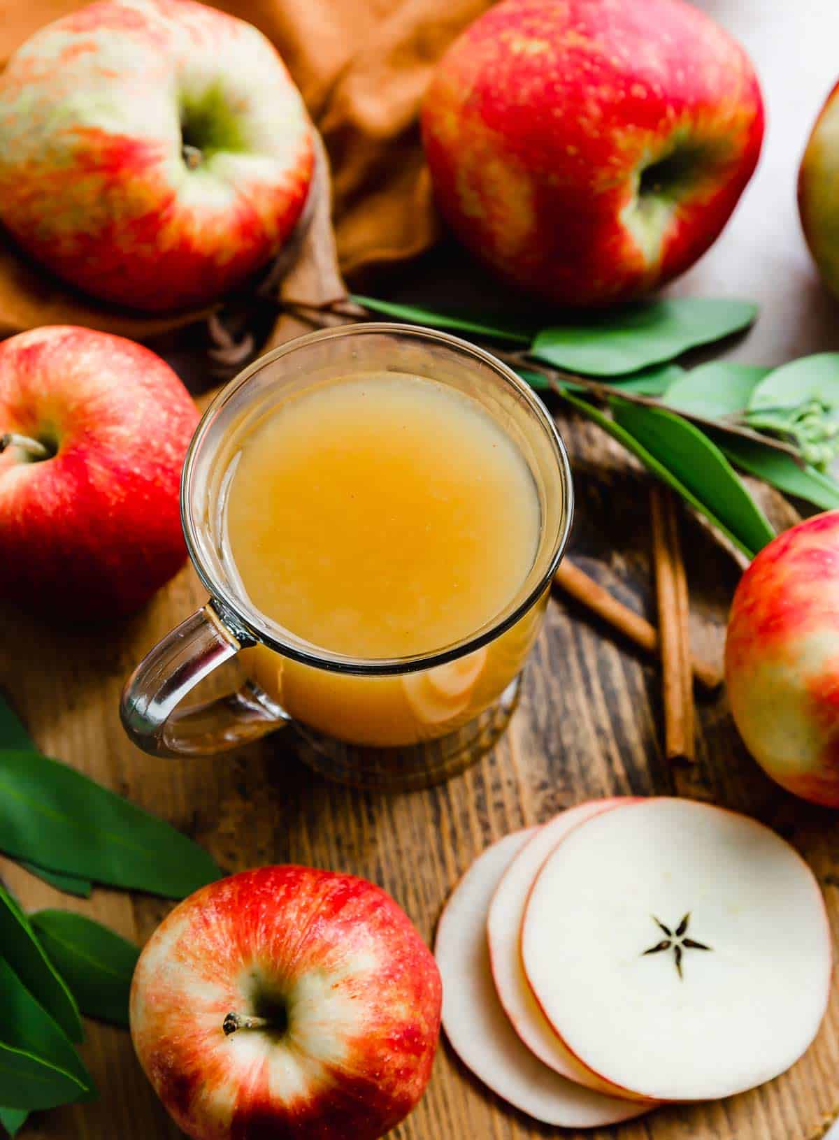 Overhead photo of Hot Wassail in a clear mug with apples surrounding the mug.
