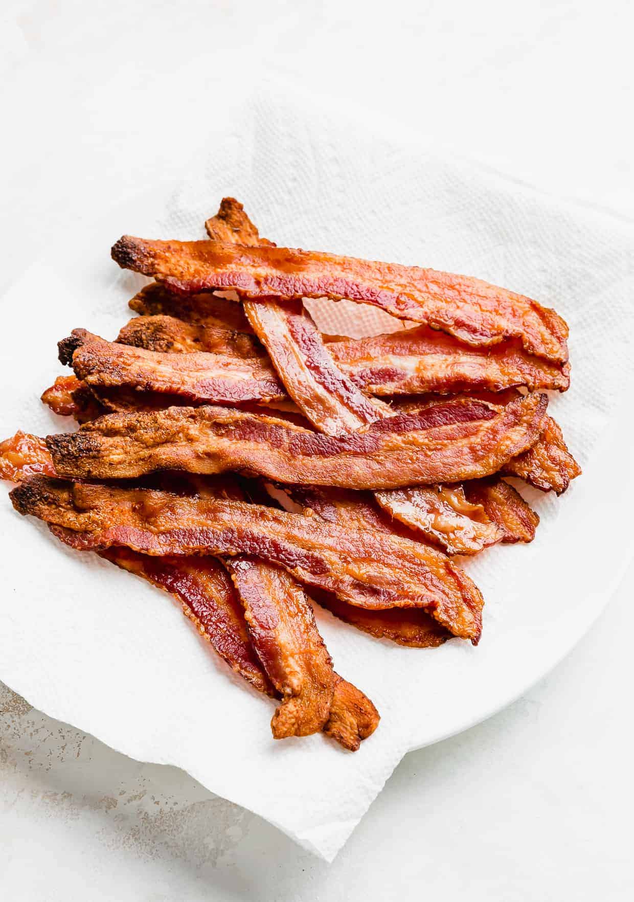 A pile of crispy bacon on a white paper towel. 