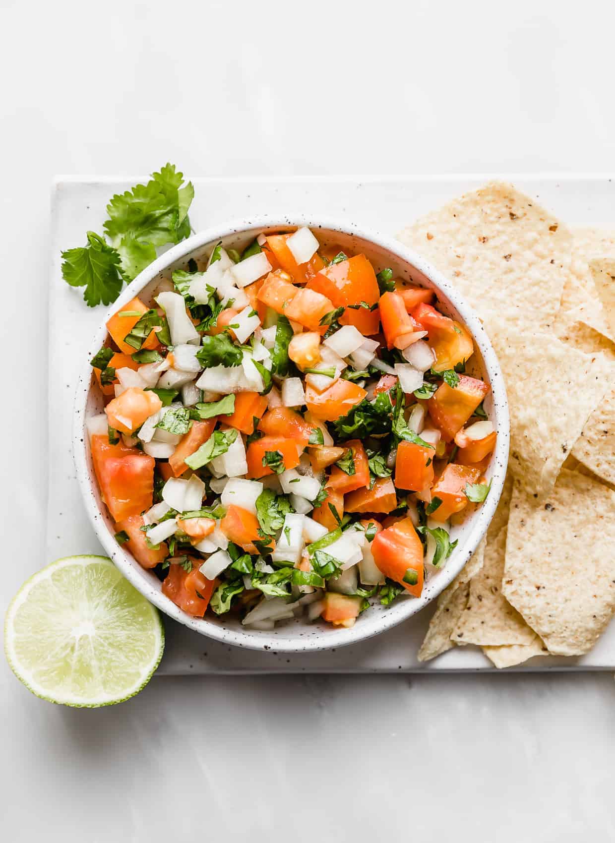 A bowl of Pico de Gallo surrounded by tortilla chips. 