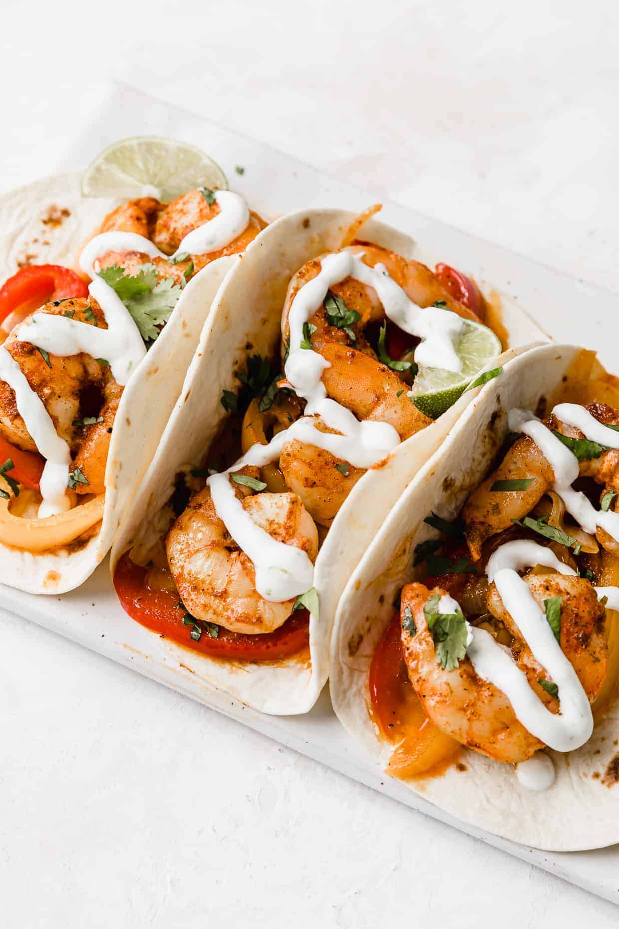 3 Shrimp fajitas with a drizzle of white Crema overtop. 