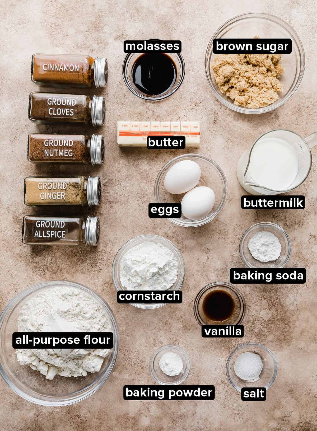 Gingerbread Waffle ingredients portioned into glass bowls on a light brown textured background.