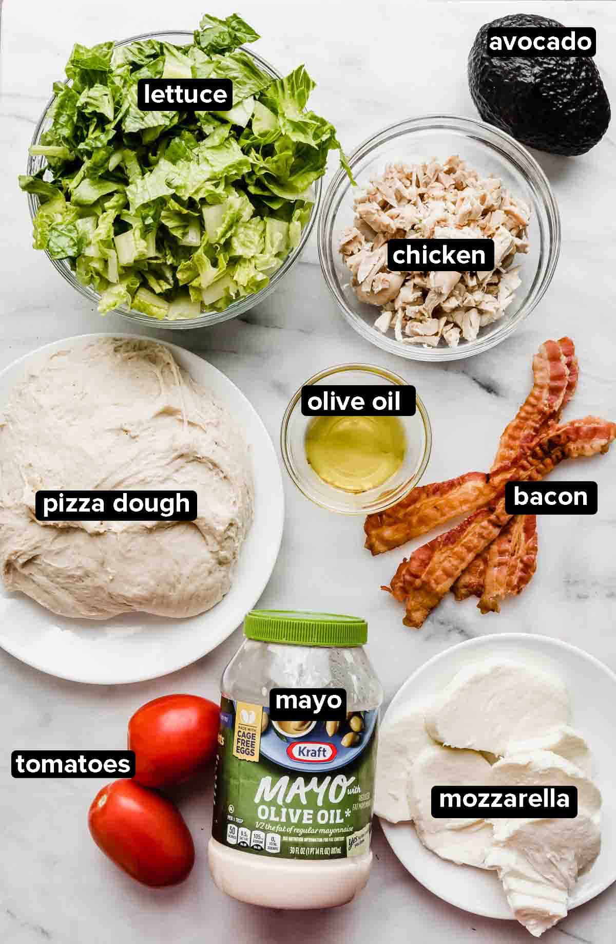 CPK Club Pizza ingredients on a white background: pizza dough, bacon, tomatoes, mayo, mozzarella, lettuce, chicken, and avocado.