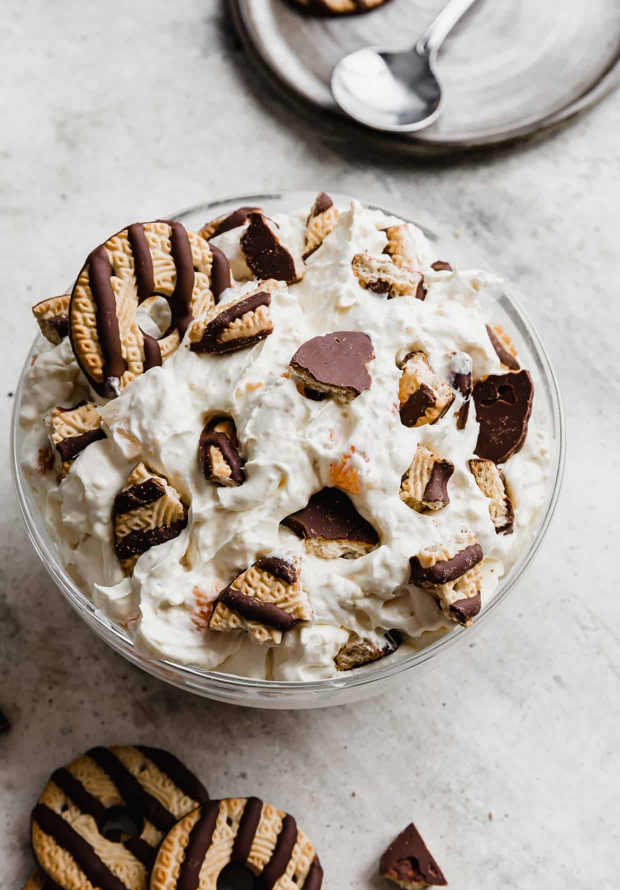 A large glass bowl full of cookie salad topped with crumbled fudge stripe cookies.
