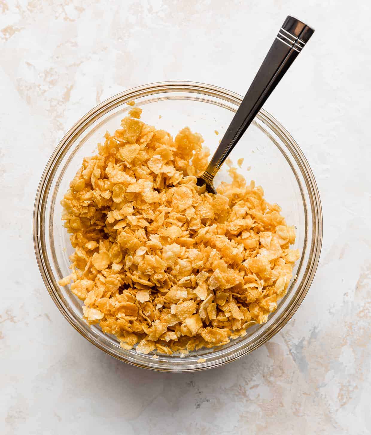 A glass bowl with crushed cornflakes in it.