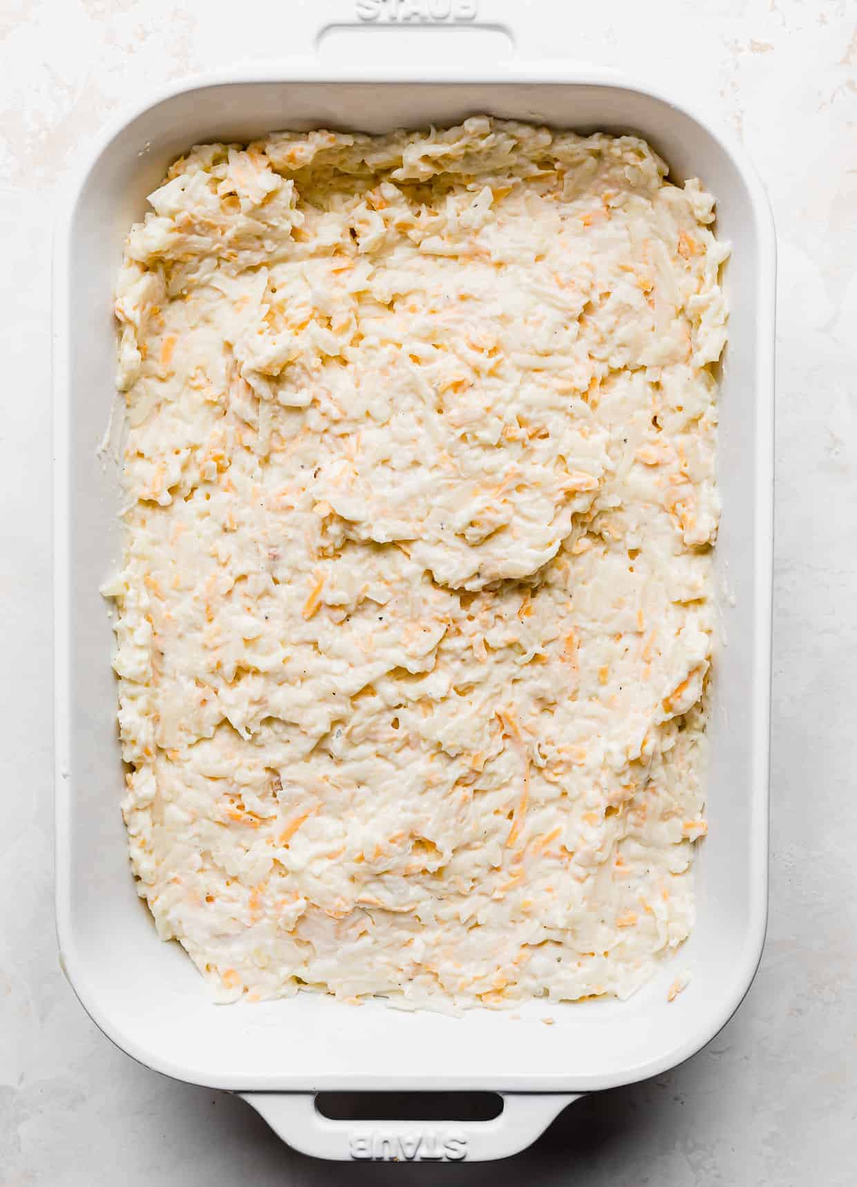 A white casserole dish full of leveled funeral potatoes against a white background.