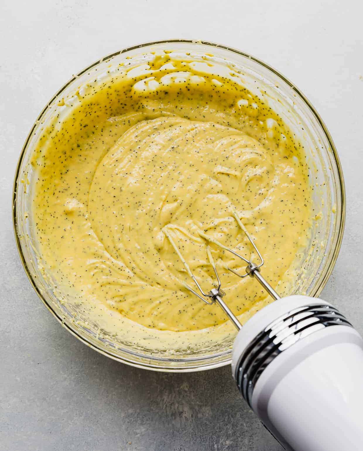 Lemon Poppy Seed Bread batter in a large glass bowl against a white background.