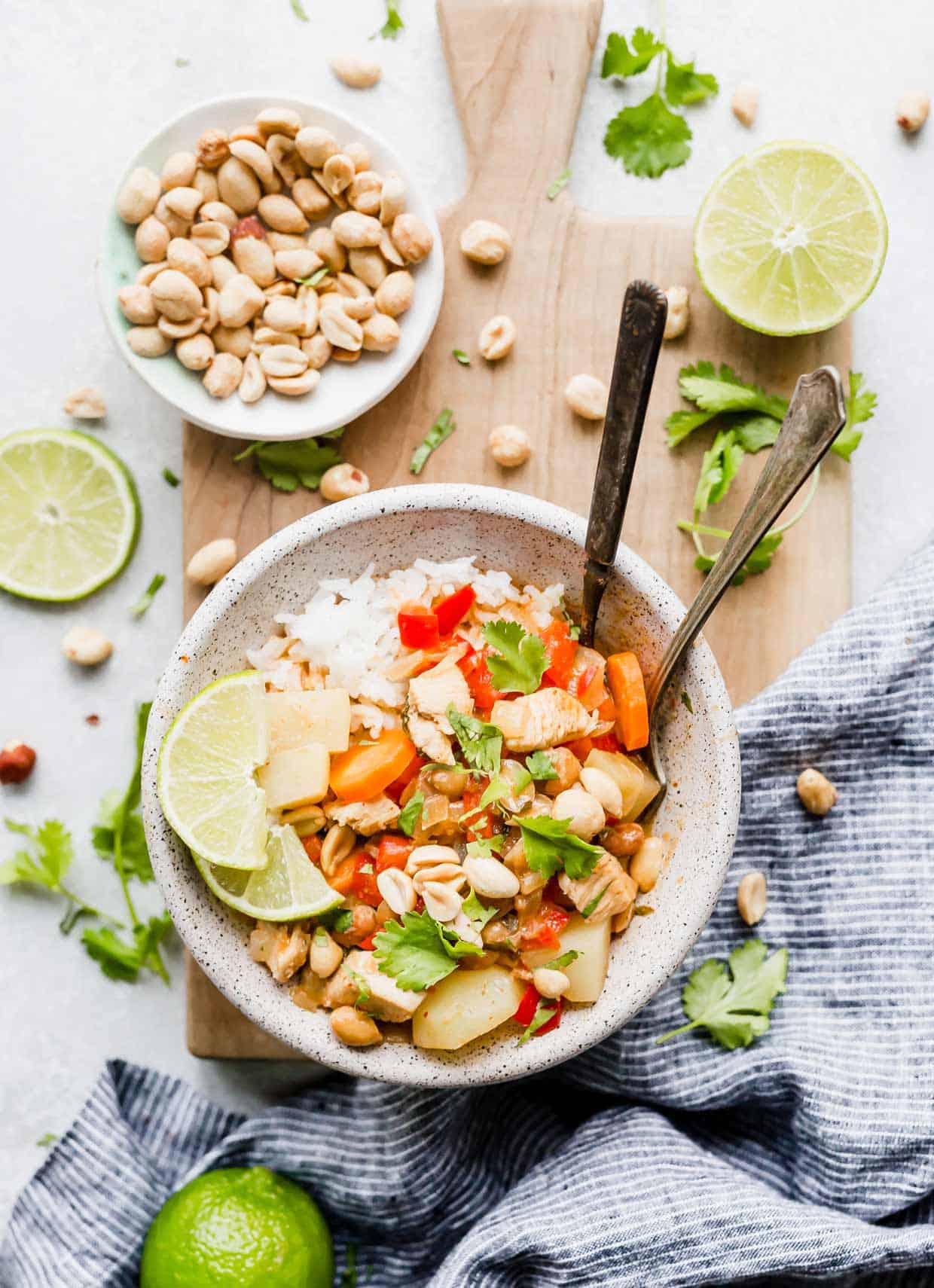 A bowl with an easy Massaman Curry topped with lime, cilantro, and peanuts.