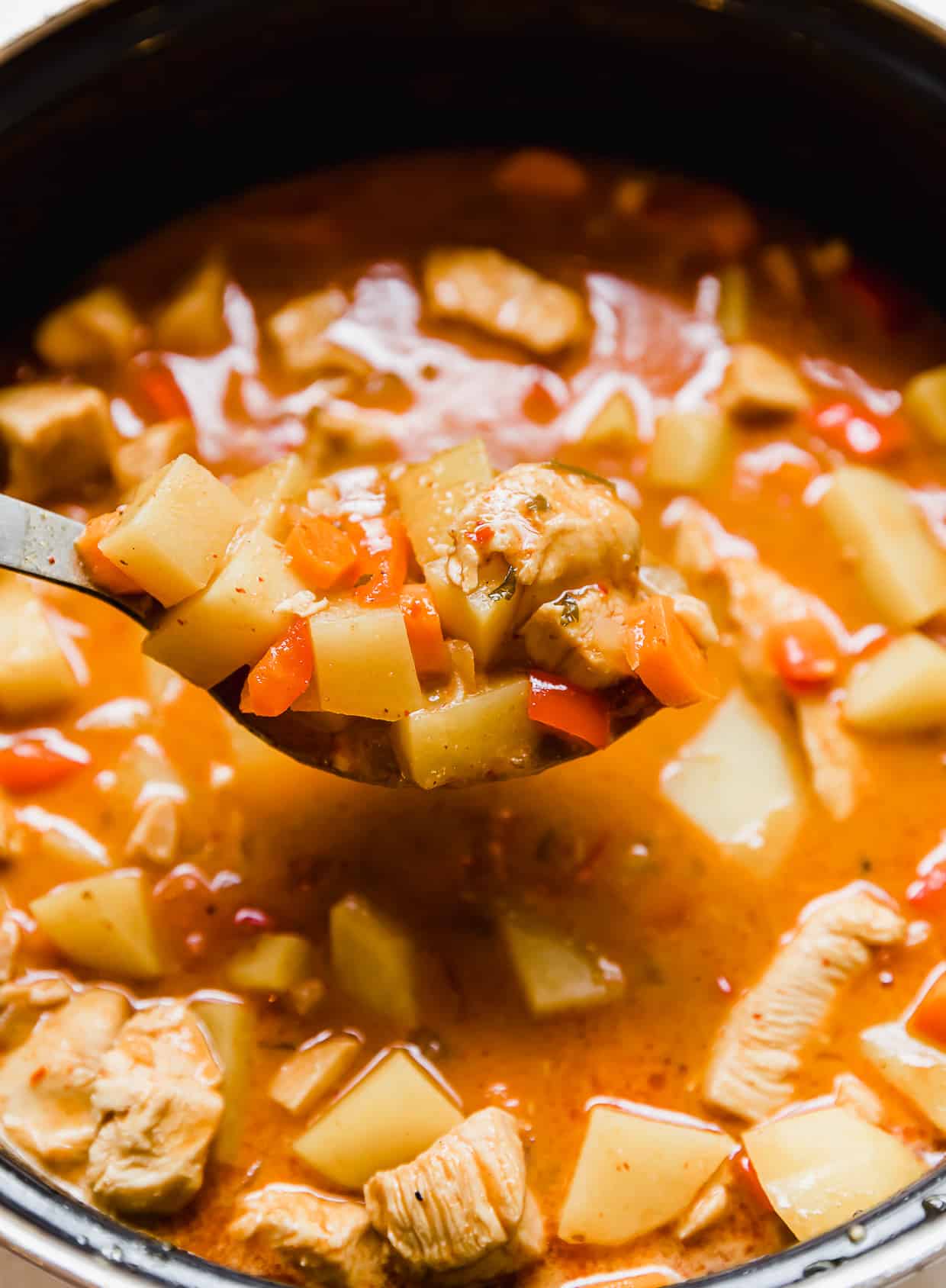 A spoon lifting upMassaman Curry from a pot.