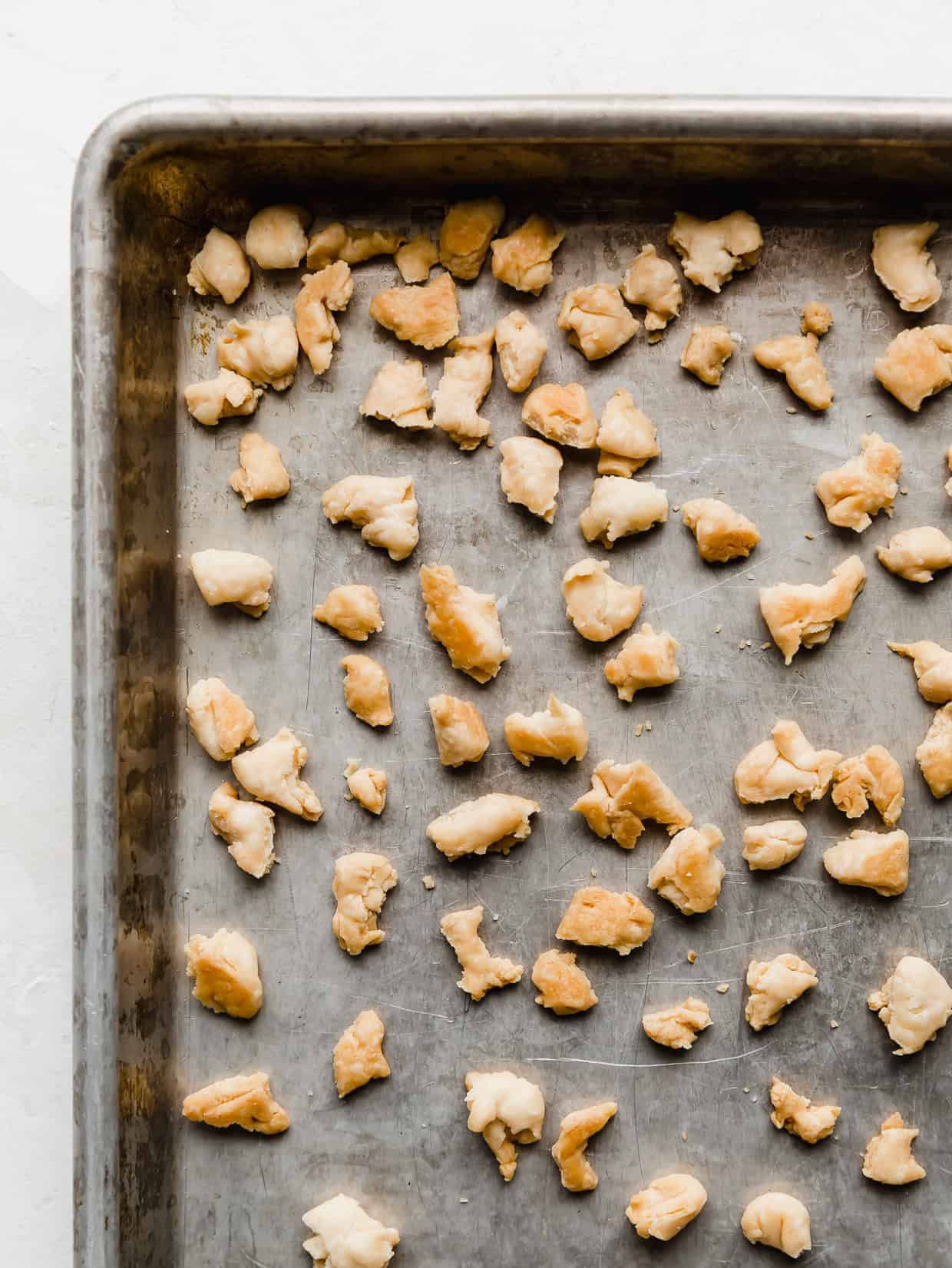 A baking sheet with golden pie crust crumbles on it.