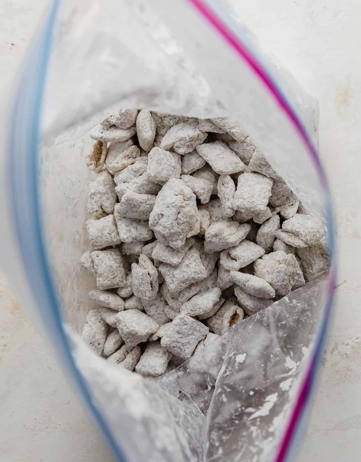 Overhead photo of an open Ziplock bag full of powdered sugar covered white Chex cereal.