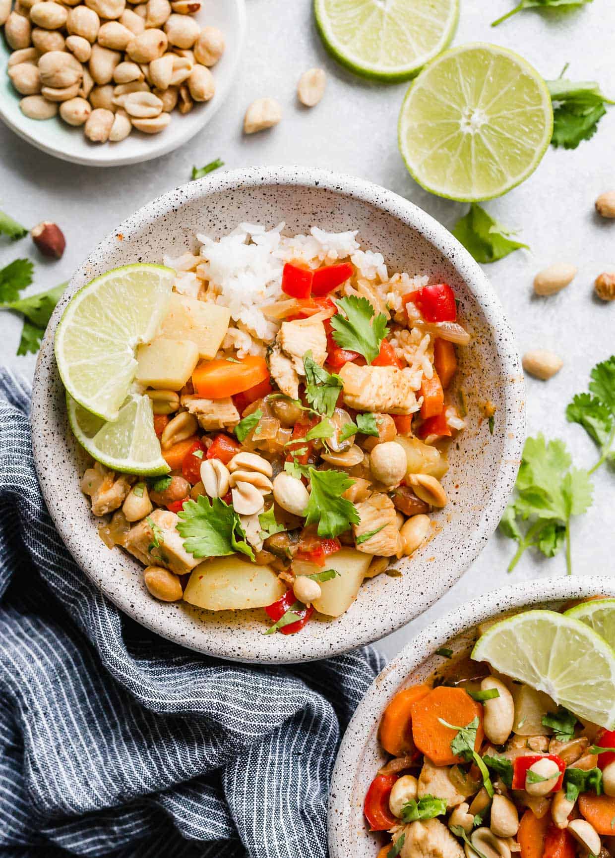 A bowl filled with white race and. Massaman Curry topped with cilantro and chopped peanuts.