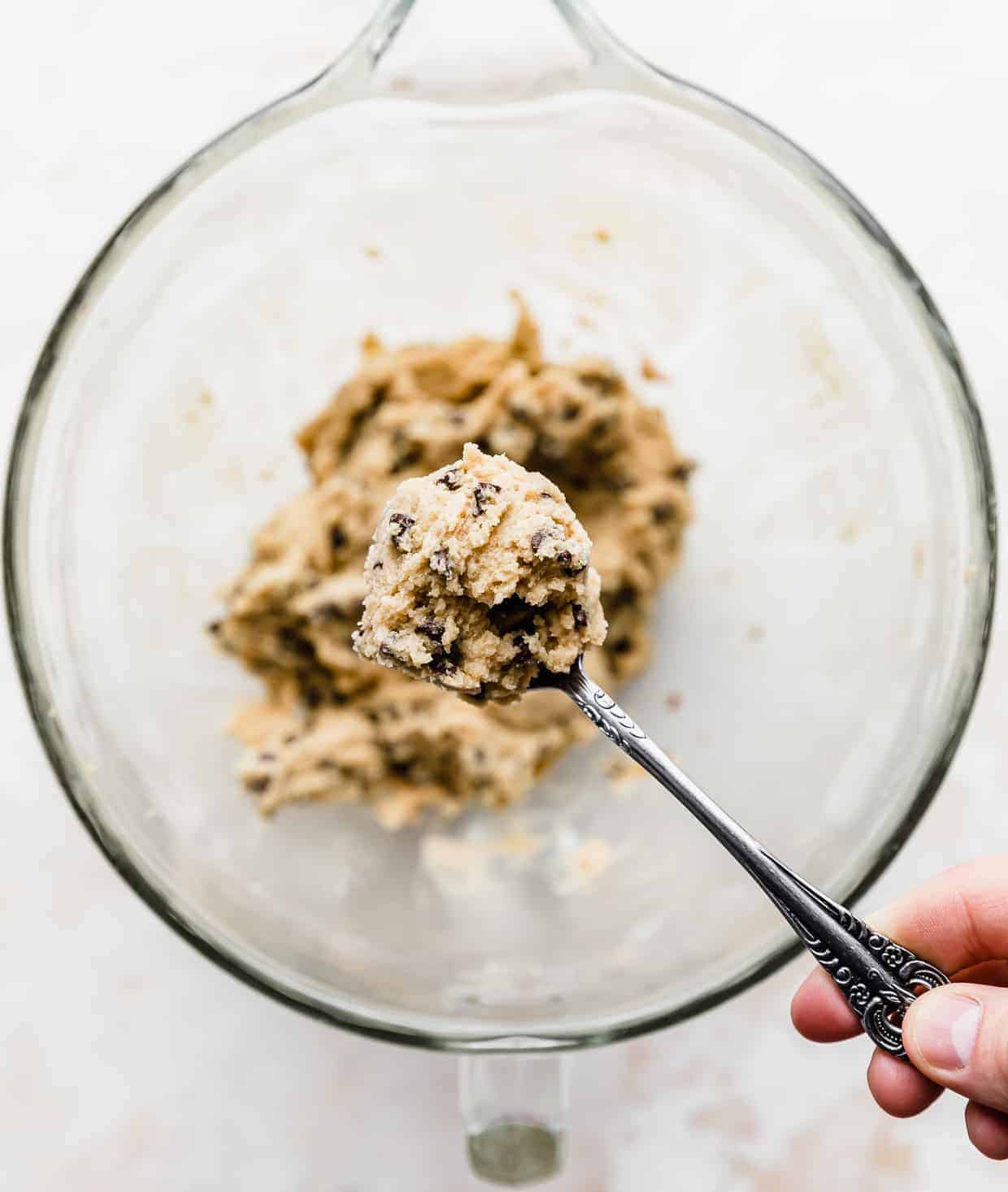 A spoon holding up a large scoop of edible homemade Ben and Jerry's Cookie Dough.