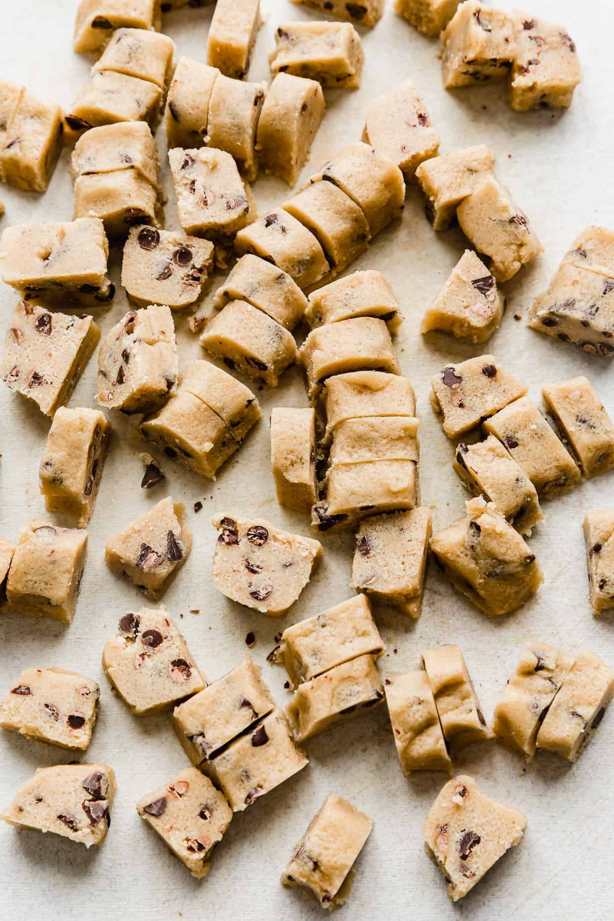 Chunks of homemade Ben and Jerry's Cookie Dough Bites on a light gray cutting board. 