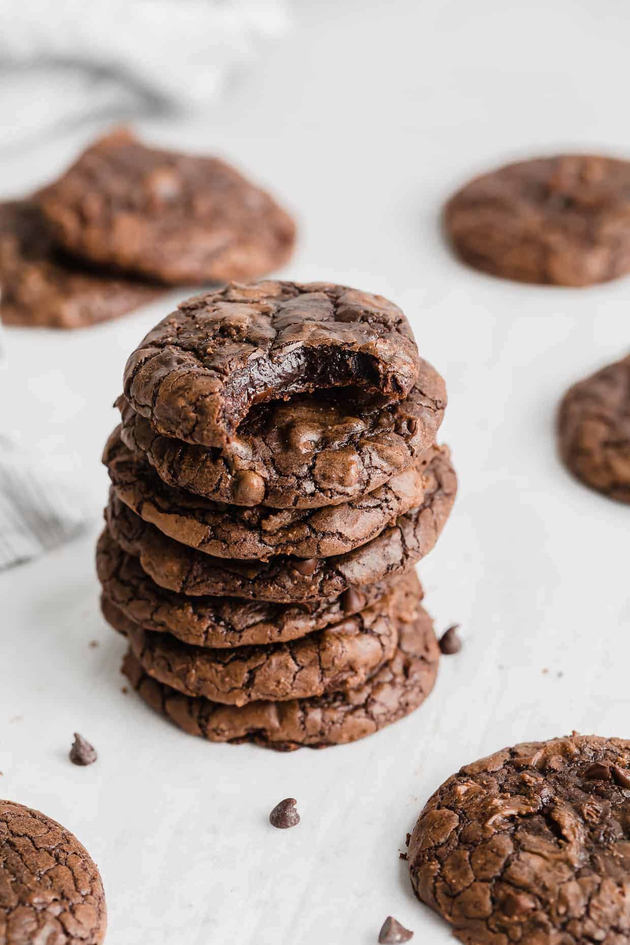 A stack of Brownie Mix Cookies against a white background with a bite taken out of the top cookie.