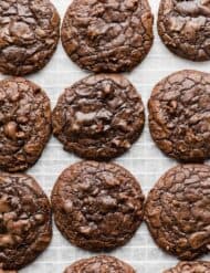 Baked brownie cookies with a crackly top studded with chocolate chips on a white background.