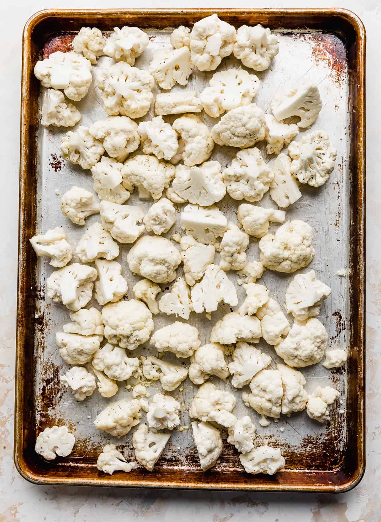 A baking sheet with raw cauliflower florets on it. 