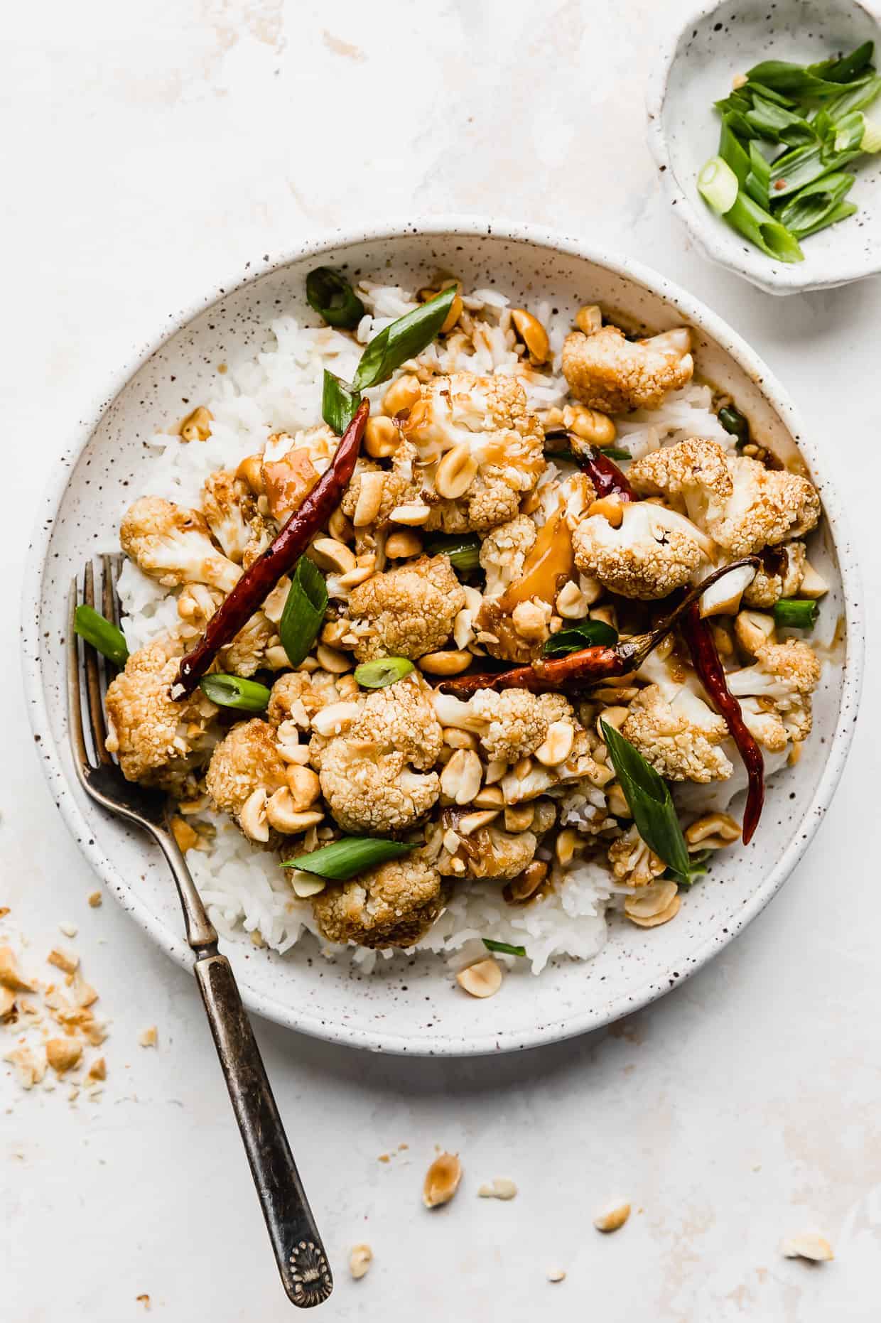 A white plate full of Kung Pao Cauliflower against a white background.