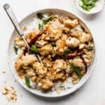 A white plate full of Kung Pao Cauliflower against a white background.