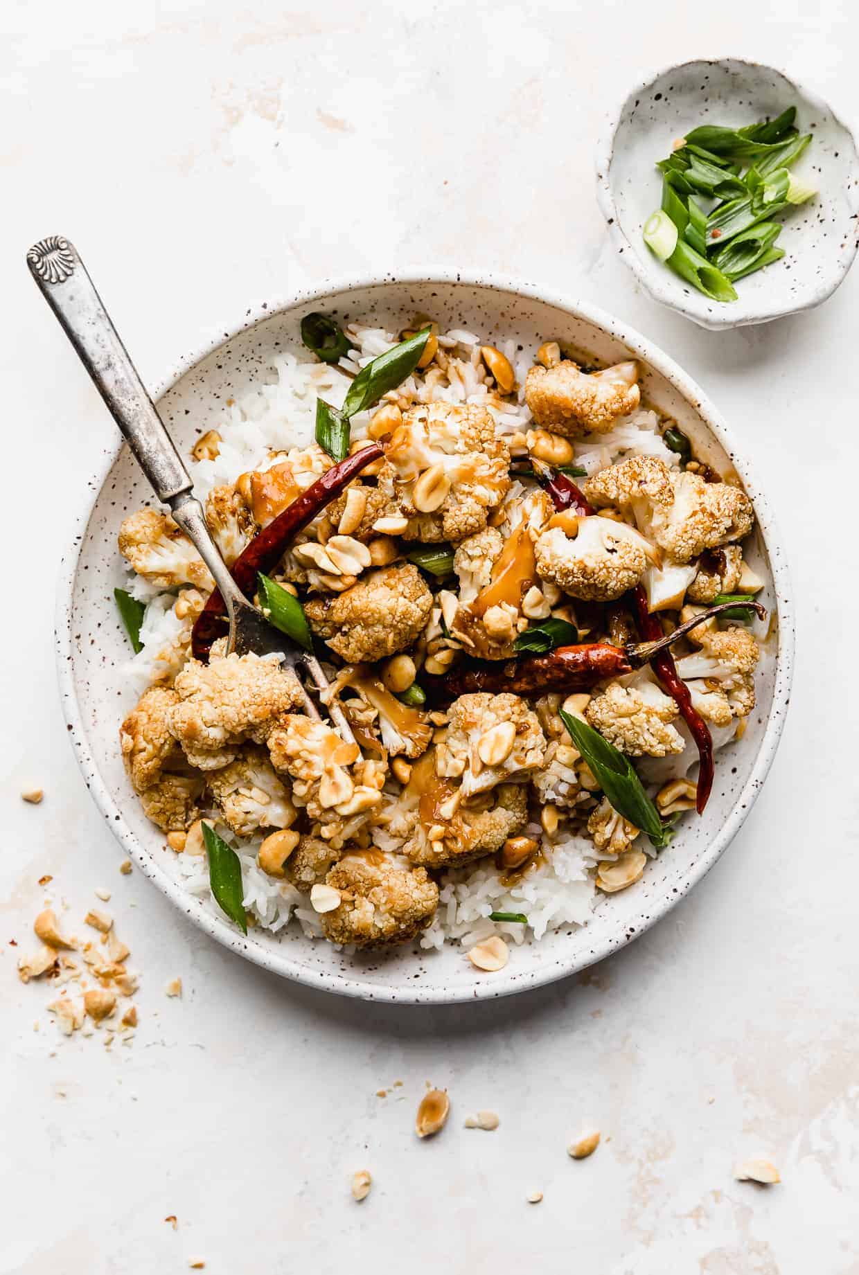 A white plate full of Kung Pao Cauliflower against a white background.