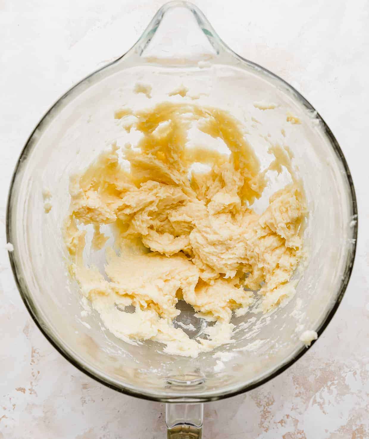 Overhead photo of a glass mixing bowl with creamed sugar cookie dough in it.