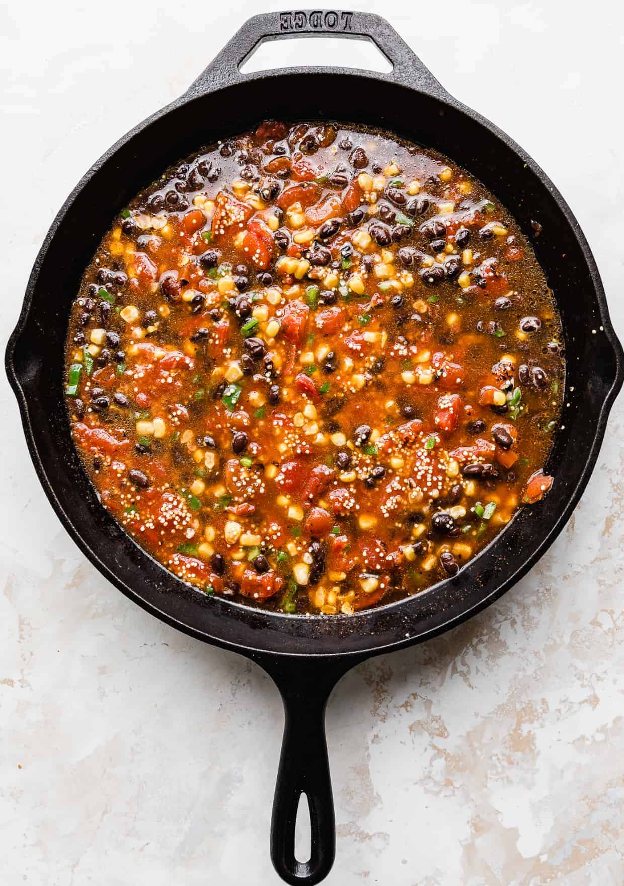 Overhead photo of a black skillet full of ingredients used to make Mexican quinoa. 