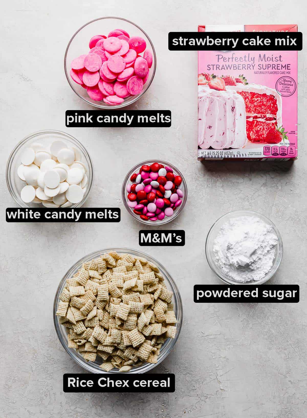 Ingredients used to make strawberry Chex mix (pink muddy buddies) on a gray background.