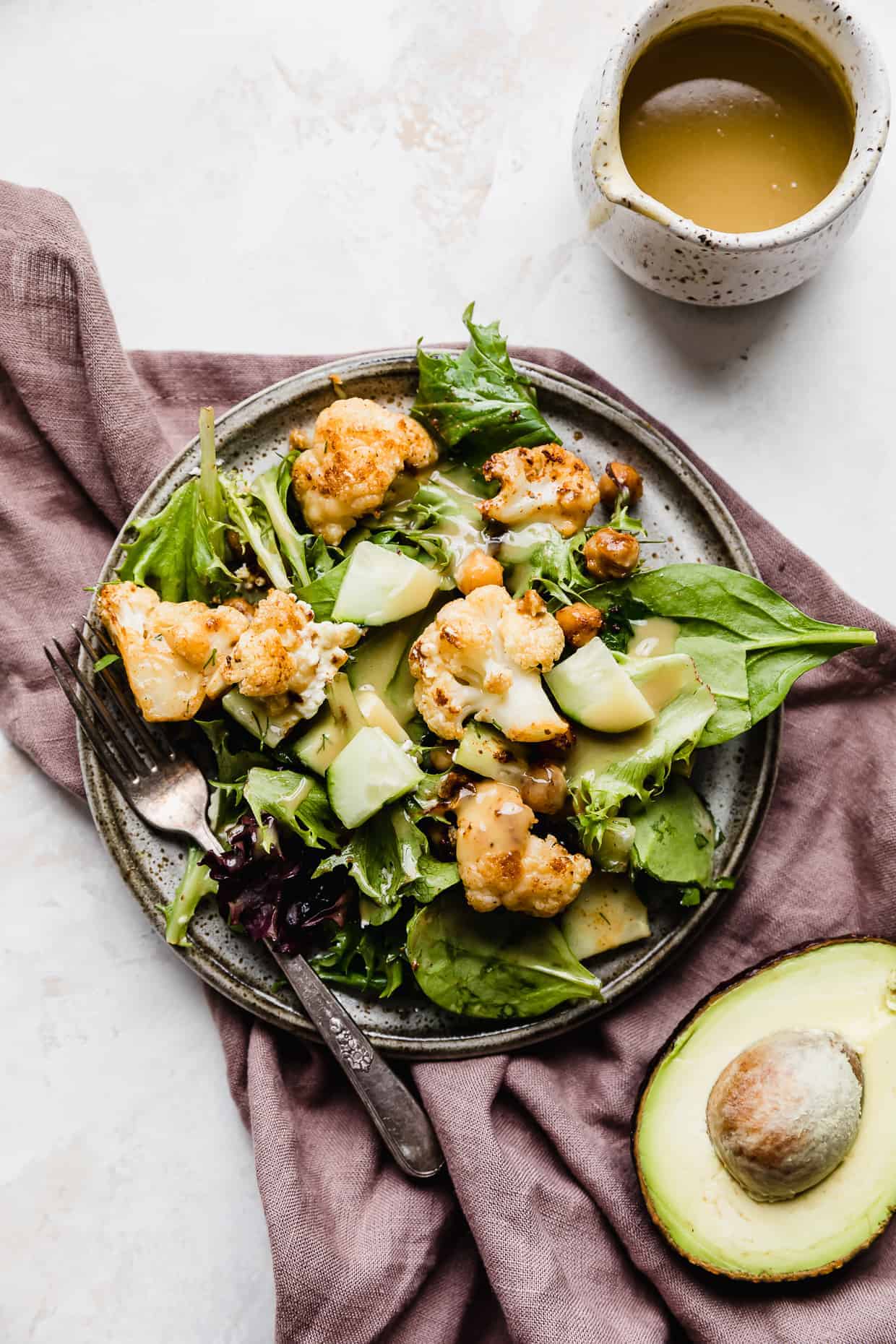 A gray plate full of Roasted Cauliflower Salad drizzled in honey mustard vinaigrette. 