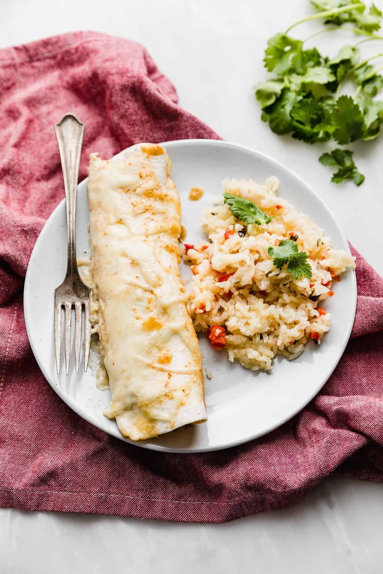 A Sweet Lime Chile Enchilada on a plate with sweet pepper rice on the side. 