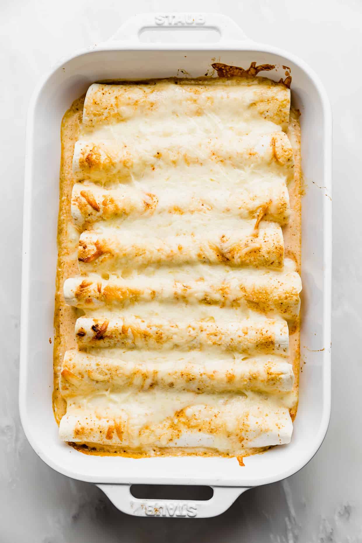 Baked Sweet Lime Chile Enchiladas in a cream and orange colored sauce topped with golden cheese. 